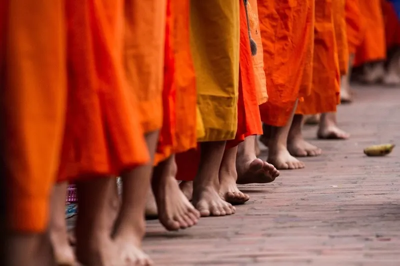 Feet of monks in orange robes in Luang Prabang